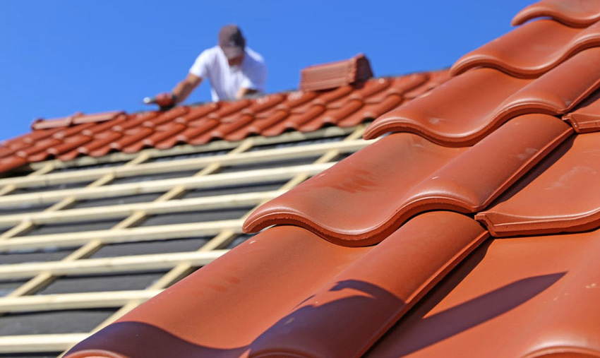Tetto in costruzione con parte di tegole posate e travatura in legno a vista